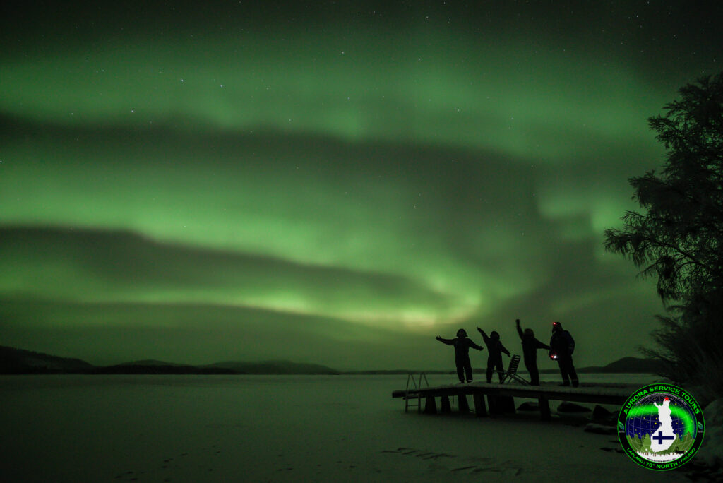 Customers standing under the aurora borealis in Lapland.